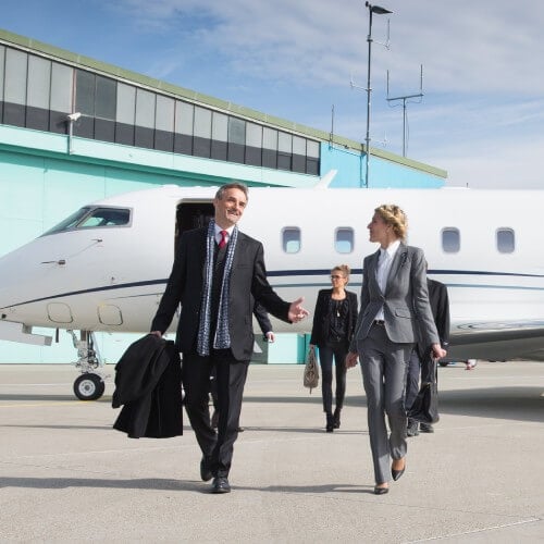 A group of business individuals approaches a luxurious private jet